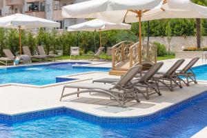 a swimming pool with lounge chairs and umbrellas at Boutique Hotel Momentum by Aycon in Budva