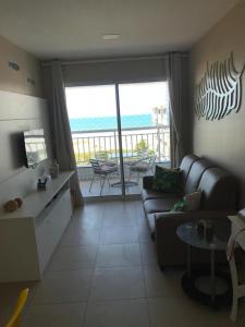 een woonkamer met een bank en uitzicht op de oceaan bij Beach Way - Apartamento no Porto das Dunas in Fortaleza