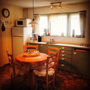 een keuken met een tafel en stoelen en een koelkast bij Huisje Stockholm op Terschelling in West-Terschelling