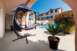 eine Terrasse mit einem Stuhl, einem Regenschirm und einer Pflanze in der Unterkunft Apartment St. Antonio in Rovinj