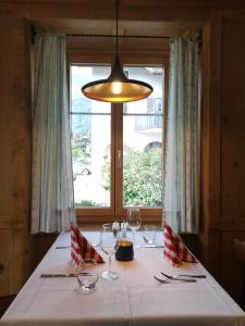 a table with wine glasses and aendant light and a window at Hotel Alpenrose in Maienfeld