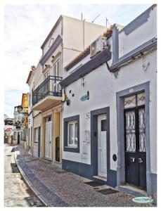 een wit gebouw met een zwarte deur op een straat bij Casinha da Ti Babel in Faro