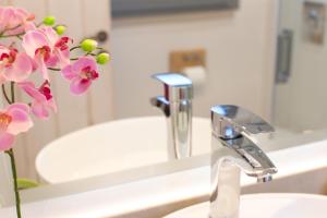 a bathroom sink with a faucet and a vase of flowers at Seaview stone apartment in Ipsos Beach in Ipsos +28 photos