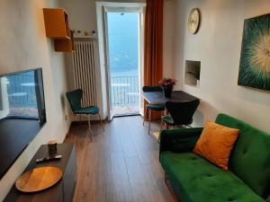 a living room with a green couch and a table at Sunset Lake Como con balcone vista lago in Blevio