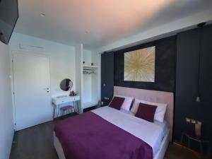 a bedroom with a large bed with a purple blanket at Le Luci sul Lago di Como in Blevio