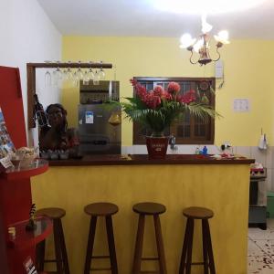 a counter with stools in a kitchen with a vase of flowers at Flat Filtro Dos Sonhos in Ilhabela