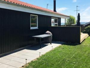 a bench sitting outside of a black house at 6 person holiday home in R nde in Rønde