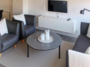 ein Wohnzimmer mit Stühlen, einem Tisch und einem TV in der Unterkunft 4 person holiday home in Bl vand in Blåvand