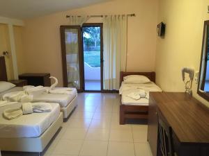 a hotel room with three beds and a balcony at Vontzos Hotel in Achladies