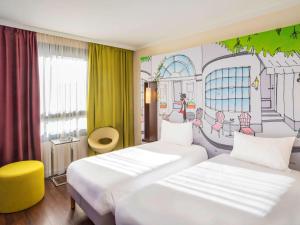 a hotel room with two beds and a drawing on the wall at ibis Styles Evry Courcouronnes Hotel and Events in Courcouronnes