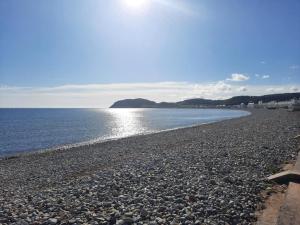 a rocky beach with the sun reflecting on the water at Lonsdale house by Orenda-Luxe in Llandudno