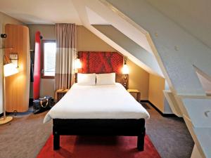 um quarto com uma cama grande e lençóis brancos em ibis Maisons Laffitte em Maisons-Laffitte