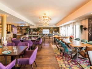 a restaurant with wooden tables and purple chairs at Mercure Hotel Bad Oeynhausen City in Bad Oeynhausen