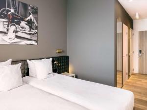 um quarto com uma cama grande e lençóis brancos em Mercure Roeselare em Roeselare