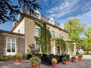 an ivy covered building with black chairs and plants at Mercure Bristol North The Grange Hotel in Bristol