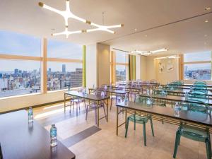 a restaurant with tables and chairs and large windows at ibis Styles Osaka Namba in Osaka