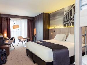 a hotel room with a large bed and a desk at Mercure Blankenberge in Blankenberge