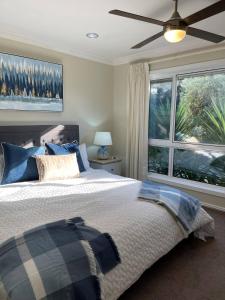 a bedroom with a bed with a ceiling fan and a window at Coastal Country Retreat, Spa, fireplace, pet friendly, FREE WIFI wine & chocolates, Kilarney, 10 minutes to Phillip Island in Kilcunda