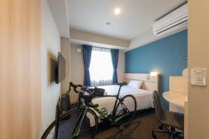 a room with a bed and a bike in a room at JRクレメントイン今治 in Imabari