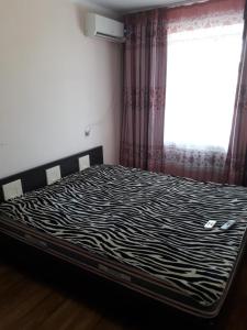 łóżko z wzorem zebry w pokoju z oknem w obiekcie Комфортная квартира для гостей города w Kyzyłordzie