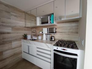 una cucina con armadi bianchi e piano cottura di Lofts do Morro Magico a Búzios