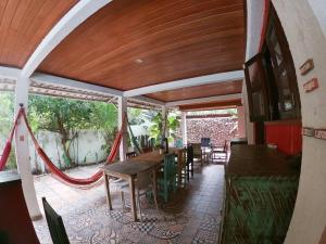 a patio with tables and chairs and a hammock at Tropical Hostel in Pipa