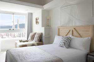 a white bedroom with a bed and a window at urban abode apartments in Taipei