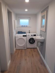a laundry room with a washing machine and a sink at Schooster Huus in Nordstrand