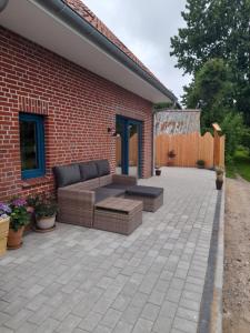 a patio with a couch and a brick building at Schooster Huus in Nordstrand