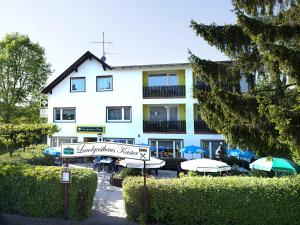 ein Gebäude mit Sonnenschirmen und Tischen davor in der Unterkunft Landgasthaus Kaster in Valwig