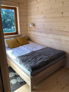 a bed in a log cabin with a window at DOMEK POD LIMBAMI III in Kluszkowce