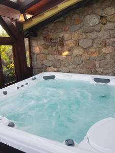 a hot tub in front of a stone wall at Podere I Casaloni - La casa nel bosco in Torniella