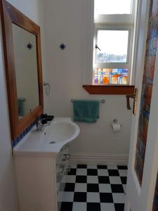 a bathroom with a sink and a mirror and a checkered floor at Old world charm in town and by the sea in Napier