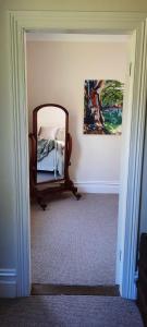 a bedroom with a mirror and a painting on the wall at Windsor House B&B in Walhalla