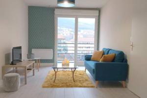 a living room with a blue couch and a table at Le Georges Marin in Bellegarde-sur-Valserine