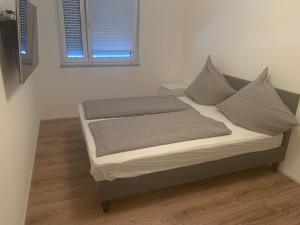 a bed with gray pillows and a window in a room at Fewo Dani in Rheinhausen +10 photos