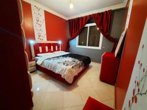 a bedroom with red walls and a bed and a window at Appartement Tanger familles in Tangier