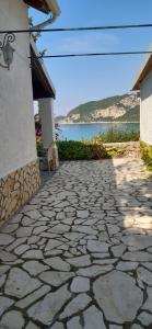 einen Steinweg neben einem Gebäude mit Blick auf das Wasser in der Unterkunft Villa Theodora View Apartments Thalia in Agios Georgios Pagon