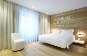 um quarto com uma cama branca e uma cadeira branca em YouMe Design Place Hotel em Trieste