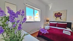 a bedroom with a red bed and purple flowers at Casa do Carmo - Fuzeta in Fuzeta