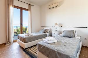 two beds in a room with a balcony at Villa AmberBlue Kalathos in Kalathos