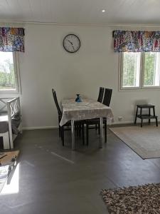 a dining room with a table and a clock on the wall at Majoitus Valkea in Nunnanen +28 photos