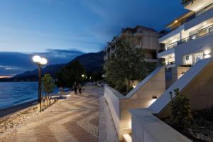 a sidewalk next to a building next to a body of water at Residence Visković in Tučepi