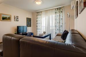 a living room with a brown leather couch and a television at Apartments Horizont in Budva