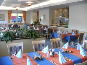 a dining room with tables and chairs with blue napkins at Hotel Sonneck in Schladming
