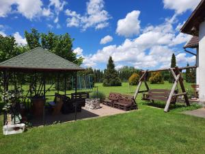 a park with two benches and a gazebo at Megálló Wellness Panzió in Pálháza