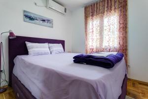 a bedroom with a bed with purple sheets and a window at Apartments Horizont in Budva