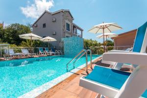 a pool with chairs and umbrellas next to a house at Apartments Horizont in Budva