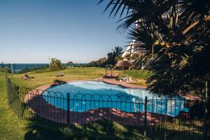 a swimming pool with a fence and a palm tree at 9 Kyalanga Beach in Durban