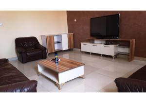 a living room with couches and a flat screen tv at Résidence Fadi Diamniadio in Dakar